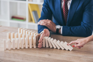 Man blocking dominos from falling showing the importance of proactive risk management